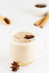 Masala chai with milk, anise, cinnamon, ginger, pepper in a glass cup. Selective focus.