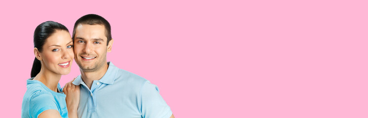 Happy amazed smiling couple. Portrait of standing close embracing pair in love studio concept, isolated on rose pink background. Young man and woman posing together. Copy space for text