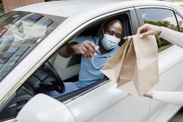 Black guy driver in face mask taking take away food