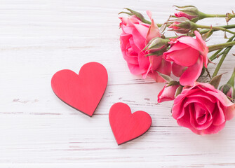 Roses and two red hearts on a white wooden background. Valentine's Day card. Wedding card