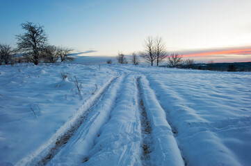 Fototapeta na wymiar Sunset in winter, car tracks in the snow.