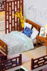 Chinese-style bedroom interior in miniature dollhouse . Toy bed with bed linen and pillows
