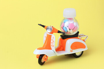 Toy scooter delivering a bottle of pills. Online delivery medicines from  pharmacy concept