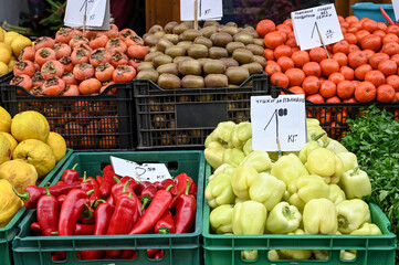 Fresh pepper, parsley, mandarins, kiwi and quince for sale at vegetable market, close up. Boxes full of raw delicious vegetable in shop. Organic vegetable at the greengrocer's stall. 