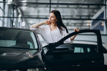 Young woman in a car showroom choosing a car