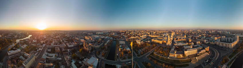 Wide panoramic aerial view above river Lopan embankment near Annunciation Cathedral in Kharkiv, Ukraine. Flagpole with flag of Ukraine and sunny autumn cityscape, city streets with traffic - obrazy, fototapety, plakaty