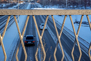 View of the highway through the pedestrian crossing fence on a winter day