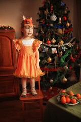 girl dressed as a Christmas chanterelle near the Christmas tree