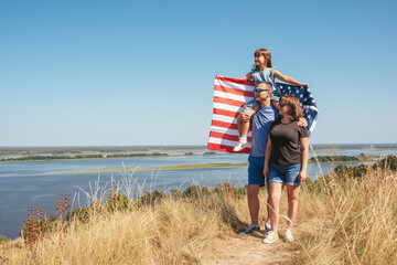 Happy family with usa flag in nature on a sunny summer day © Andrii