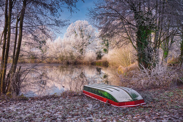 Verschneite Winterlandschaft mit Boot und B&auml;umen am See