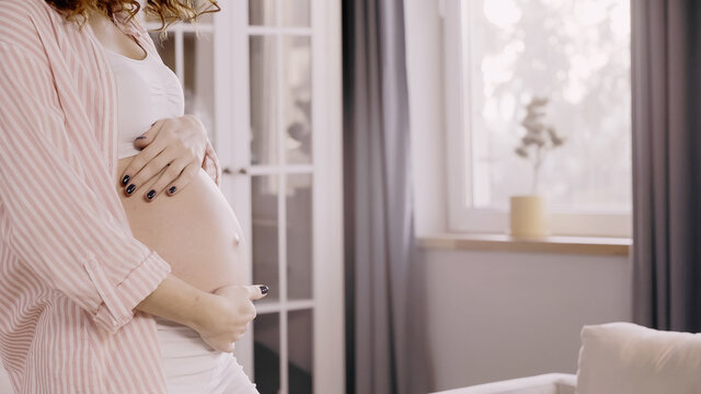 Cropped view of pregnant woman touching belly at home