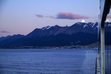 Amazing and breathtaking full moon scenery over Patagonia during early morning with city of...