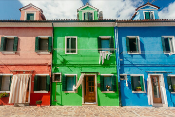 Fototapeta na wymiar Red, green, blue houses of Burano island with small streets on sunny day. Venice area.