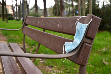 Used protective mask abandoned on a park bench. Used Protective masks abandoned during the Coronavirus pandemic on public places.