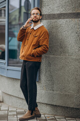 Obraz premium Young handsome man talking on tha phone in winter jacket in the street