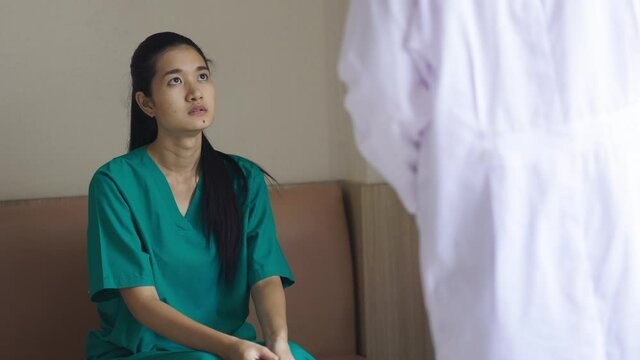 Young woman patient talking with doctor. Asian man doctor examining chest x-ray film of woman patient at hospital. Healthcare and medical concept.