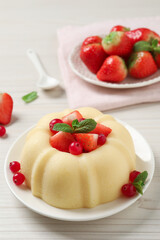 Delicious semolina pudding with berries on white wooden table