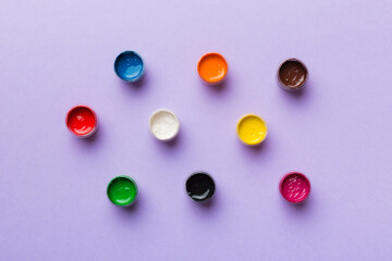 jars with gouache of different colors on Colored background. hobby painting. Top view with empty space. workplace for creativity. home teaching concept drawing