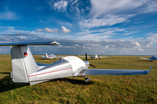 Flugplatz auf Juist mit einigen Sportflugzeugen auf einer Wiese mit blauen, dramatischen Himmel