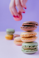 Feminine hand with macarons dessert on pastel tones background. Copy space.
