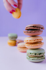 Feminine hand with macarons dessert on pastel tones background. Copy space.
