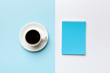 Modern office desk table with notebook and other supplies with cup of coffee. Blank notebook page for you design. Top view, flat lay