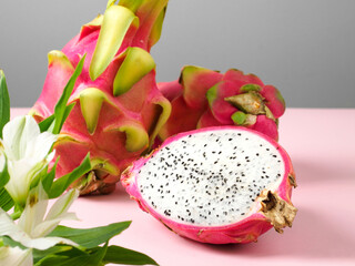 Delicious cut and whole dragon fruits pitahaya on color pink and grey background. Sunny tropical...
