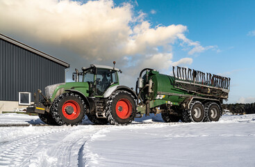 Wintereinbruch in der Landwirtschaft, Traktor mit Güllefass im Schnee.
