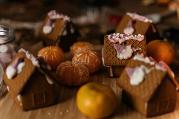 Christmas cooking gingerbread houses and ginger cookies on the kitchen table with tangerines.