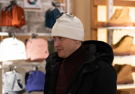 Photo of a man choosing a winter hat for himself. Hat for the cold season and sports.