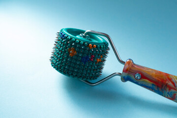 Roller Lyapko for massage and rehabilitation on a blue background. Device massager Lyapko with needles. Spiky roller with metal needles. 