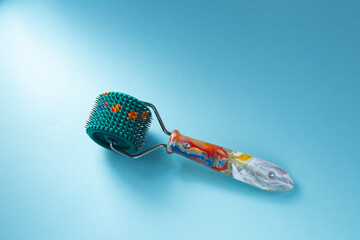 Roller Lyapko for massage and rehabilitation on a blue background. Device massager Lyapko with needles. Spiky roller with metal needles. 