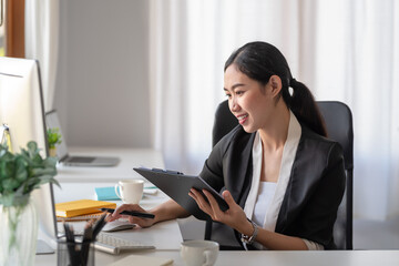 Smiling happy young Asian businesswoman working with laptop computer in office