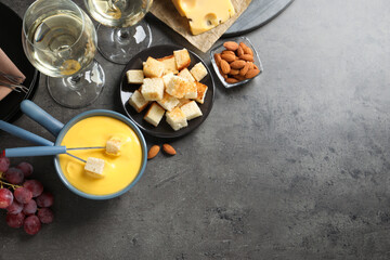 Flat lay composition with pot of tasty cheese fondue on grey table. Space for text