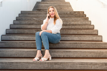 a businesswoman sitting on the stairs talking on her cell phone