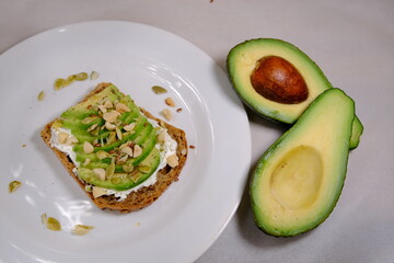 Avocado sandwiches, half of avocado, with peanuts and pumpkin seeds on a white background and divided avocado fruit near