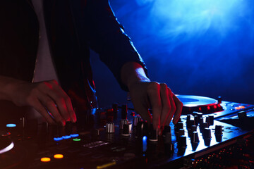DJ creating music on modern console mixer in night club, closeup