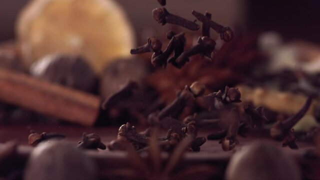 Clove falling among Spices on wood. Slow motion