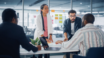 Multi-Ethnic Office Conference Room Businesspeople Meeting at Big Table. Diverse Team of Creative Entrepreneurs Talk, Use Laptop. Specialists work in Digital e-Commerce Startup.