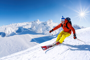 Skier skiing downhill in high mountains against blue sky - obrazy, fototapety, plakaty