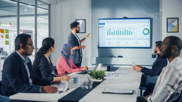 Diverse Office Conference Room Meeting: Successful Hispanic Top Manager Presents e-Commerce Software Company Growth Statistics to a Group of Investors. Wall TV with Big Data Analysis, Infographics