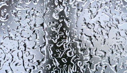 Texture of frozen water drops on the glass. Dark triangle silhouette on the background. High quality macro photo.