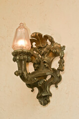 front view, medium distance of a bronze detailed light fixture hanging on an interior wall of a tropical estate 