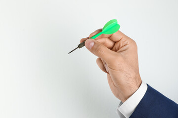 Man holding green dart on light background, closeup. Space for text