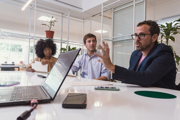 Latino adult man with beard and glasses explaining business in executive meeting