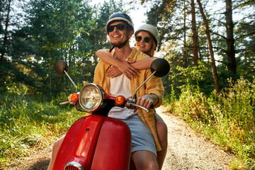 Happy young caucasian man and woman riding scooter