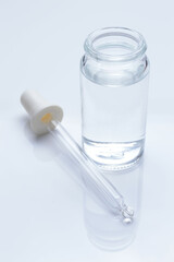 glass transparent jar and a cosmetic pipette with liquid droplets on a white background.