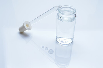 Fototapeta na wymiar glass transparent jar and a cosmetic pipette with liquid droplets on a white background.