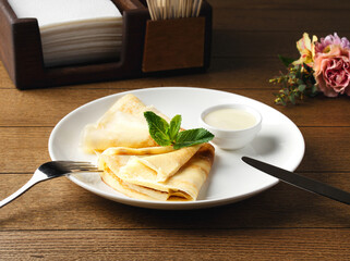 Bowl of condensed milk and pancakes served on wooden table, top view. Breakfast at the hotel, cafe, restaurant. Copy space. Morning. Food photography. Pancakes with mint. Russian breakfast.