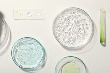 Flat lay composition with cosmetic gel and laboratory glassware on white background